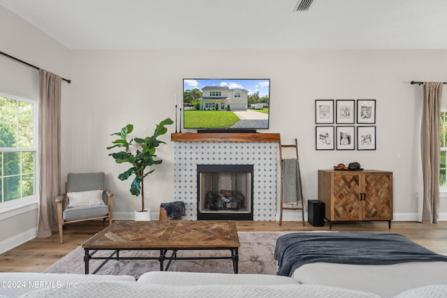 living area featuring a fireplace, baseboards, and wood finished floors