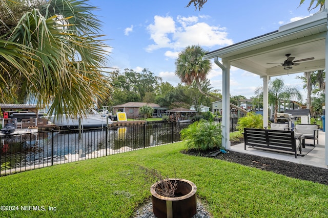 view of yard featuring a patio, outdoor lounge area, a water view, fence, and a ceiling fan