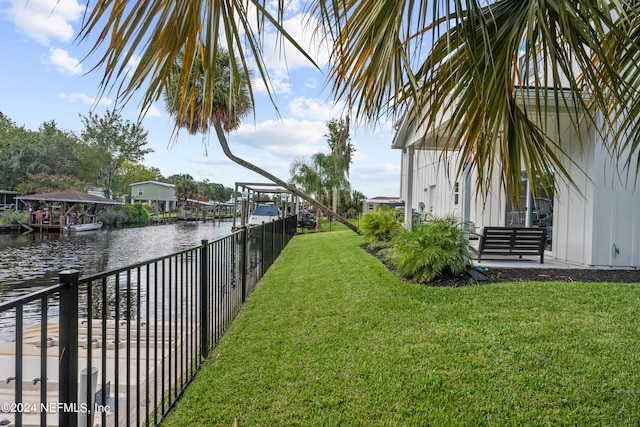 view of yard with a water view, fence, and a boat dock