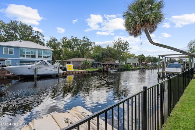 water view with a boat dock, boat lift, and fence