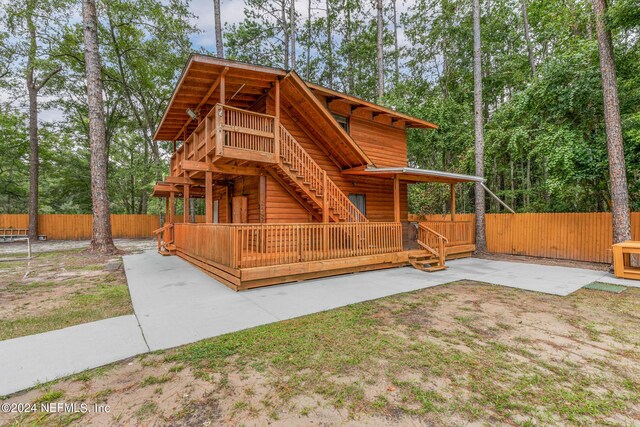 log-style house with a wooden deck and a patio