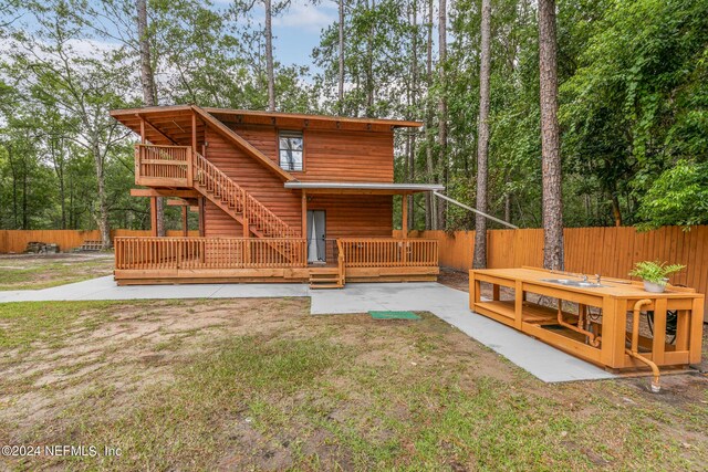 rear view of property featuring a lawn, a patio, and a deck