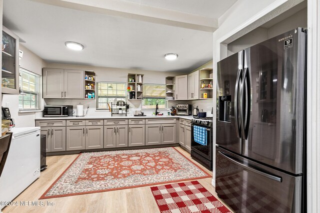 kitchen with stainless steel appliances, sink, gray cabinets, and light wood-type flooring