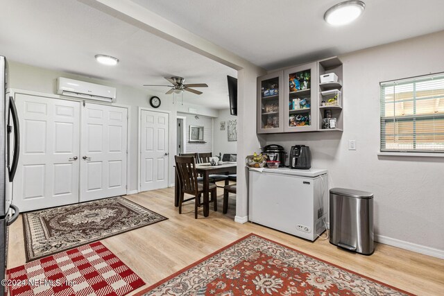 entrance foyer with light hardwood / wood-style flooring, ceiling fan, and a wall unit AC