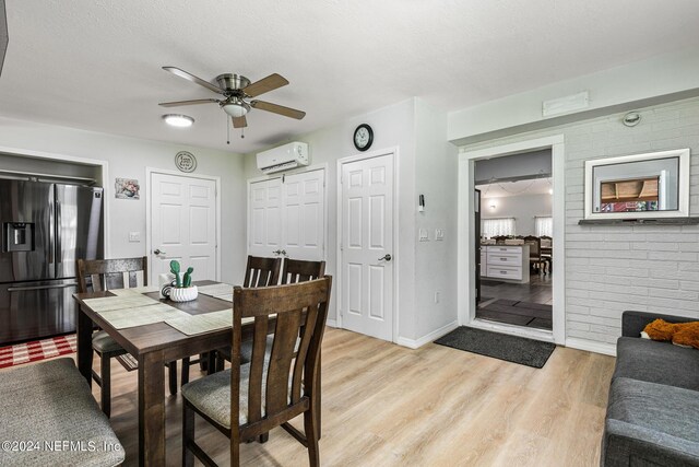 dining room with ceiling fan, a textured ceiling, an AC wall unit, and light hardwood / wood-style flooring