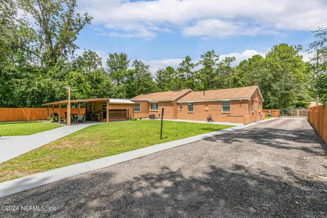 ranch-style home featuring a carport and a front yard