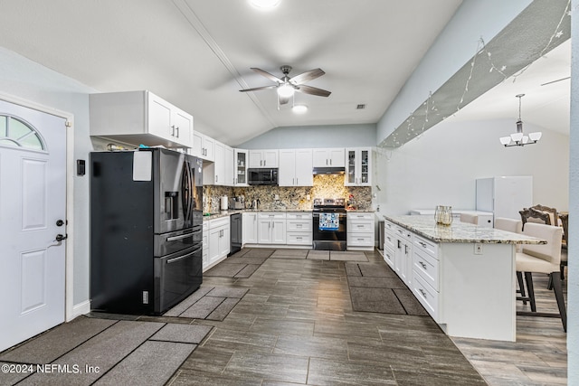 kitchen featuring vaulted ceiling, black appliances, a kitchen bar, white cabinetry, and ceiling fan