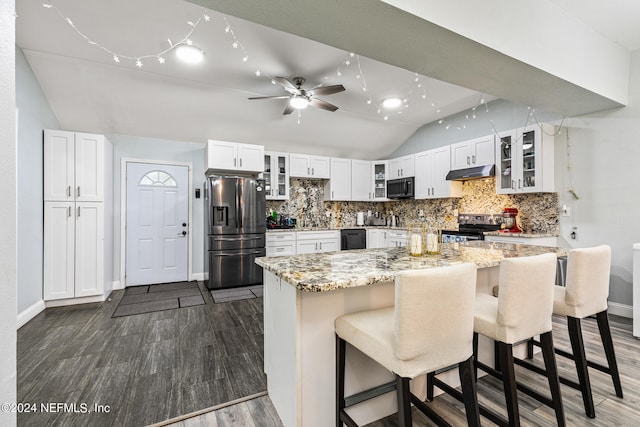 kitchen with a kitchen bar, black appliances, ceiling fan, vaulted ceiling, and white cabinets