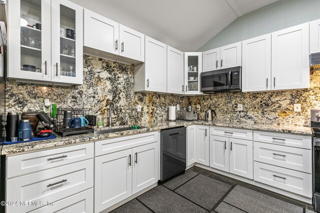 kitchen featuring white cabinets, vaulted ceiling, sink, black dishwasher, and tasteful backsplash