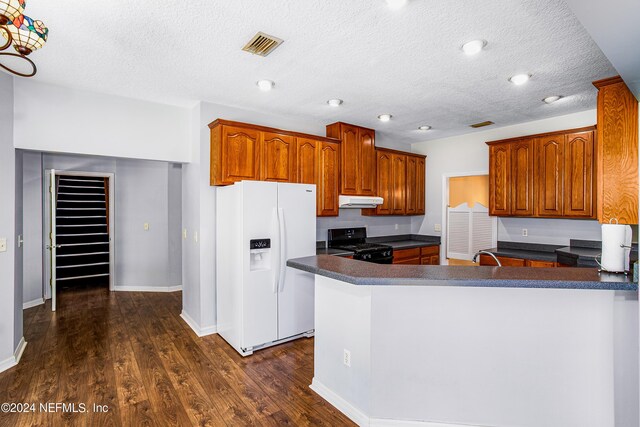 kitchen with black gas range oven, white refrigerator with ice dispenser, kitchen peninsula, dark wood-type flooring, and a textured ceiling