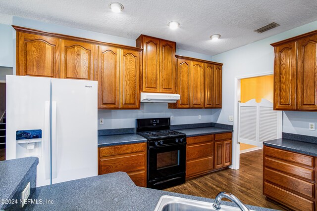 kitchen with gas stove, sink, dark wood-type flooring, white fridge with ice dispenser, and a textured ceiling