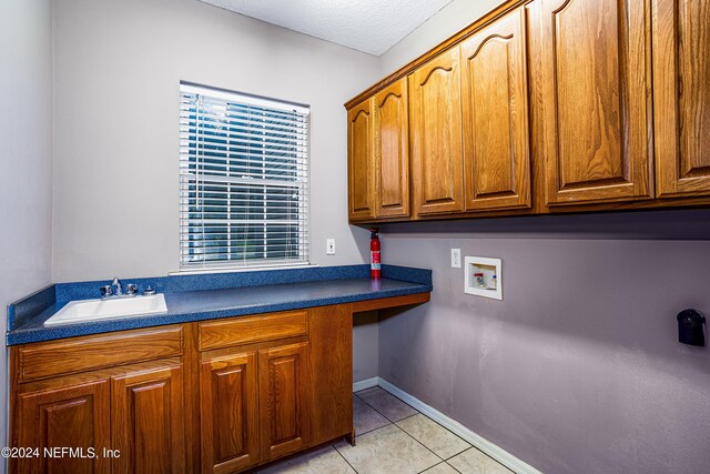 clothes washing area featuring cabinets, hookup for a washing machine, a textured ceiling, light tile patterned floors, and sink