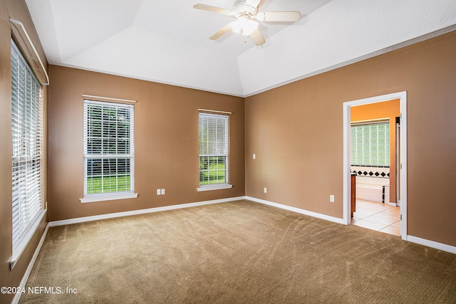 unfurnished bedroom featuring lofted ceiling, ceiling fan, ensuite bathroom, and light carpet