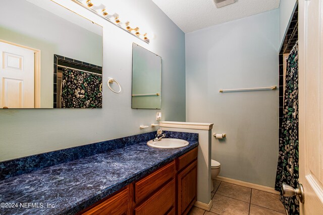 bathroom with toilet, walk in shower, tile patterned flooring, vanity, and a textured ceiling