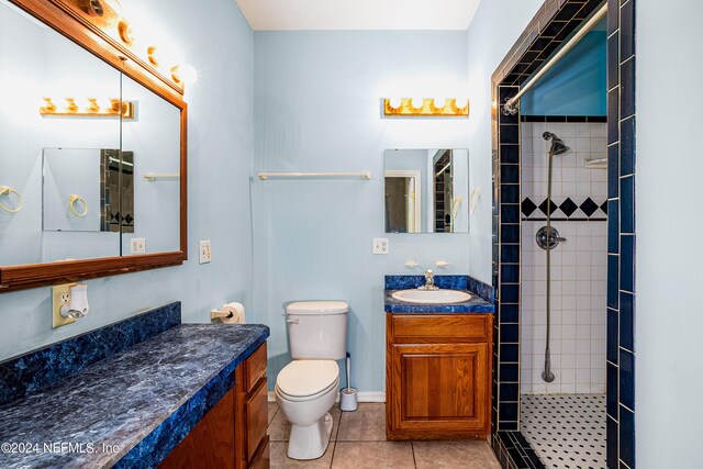 bathroom featuring vanity, toilet, tile patterned floors, and a tile shower