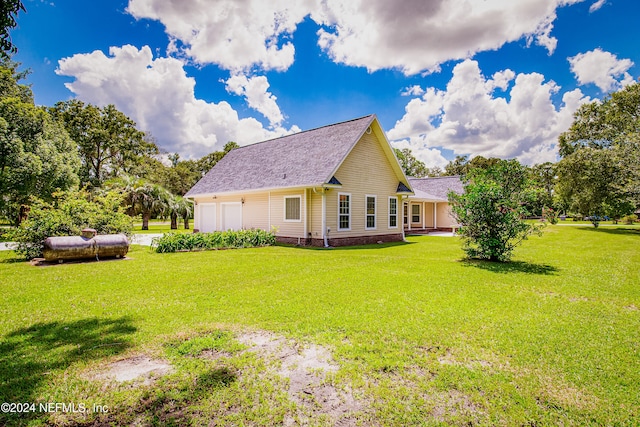 back of house featuring a lawn and a garage