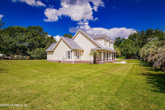 rear view of property featuring a lawn and covered porch