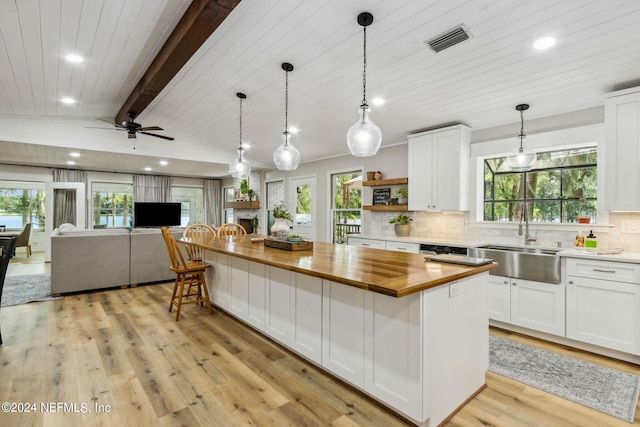 kitchen featuring light hardwood / wood-style floors, a center island, a large fireplace, ceiling fan, and white cabinets