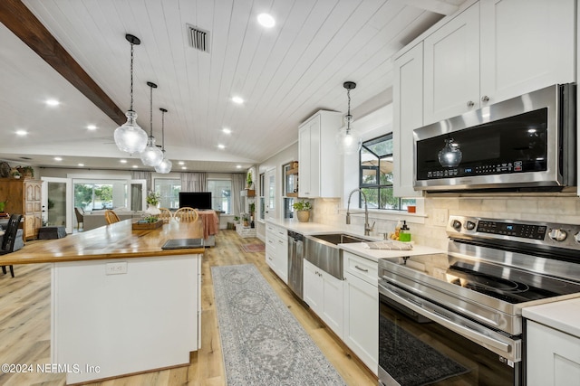 kitchen featuring wooden counters, appliances with stainless steel finishes, a center island, and a healthy amount of sunlight