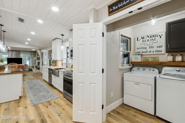 laundry room with washing machine and clothes dryer, sink, light wood-type flooring, and wooden ceiling