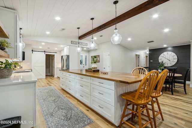 kitchen with white cabinetry, a spacious island, wooden counters, a breakfast bar, and a barn door