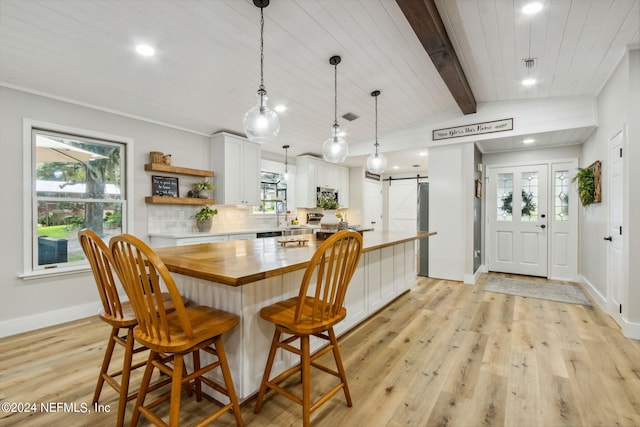 dining area with a barn door, wooden ceiling, lofted ceiling with beams, and light hardwood / wood-style flooring