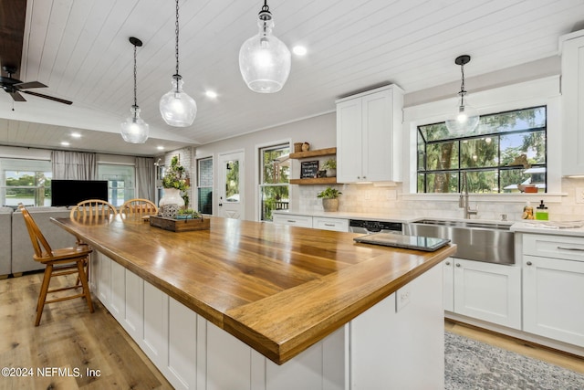 kitchen with ceiling fan, a kitchen island, white cabinetry, and wood counters