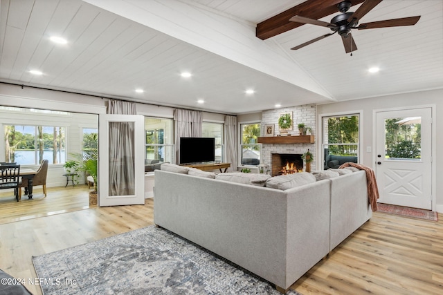 living room featuring a wealth of natural light, light hardwood / wood-style floors, ceiling fan, and a fireplace