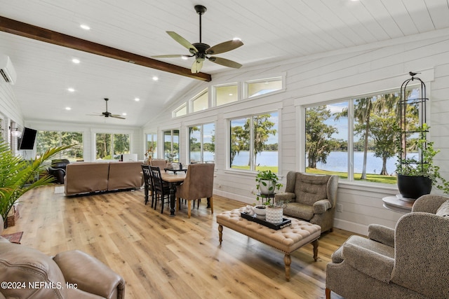 living room featuring plenty of natural light, wood walls, and a water view