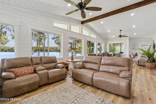 living room featuring a water view, wood walls, ceiling fan, vaulted ceiling with beams, and light hardwood / wood-style floors