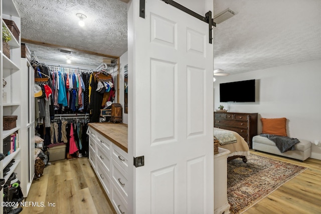 walk in closet with light wood-type flooring and a barn door