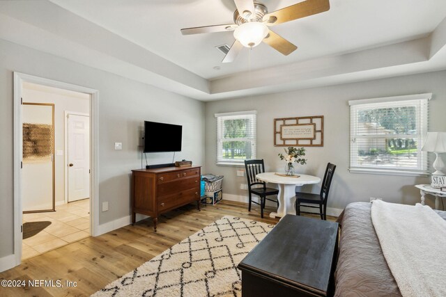 living room featuring a wealth of natural light, light hardwood / wood-style flooring, ceiling fan, and a tray ceiling