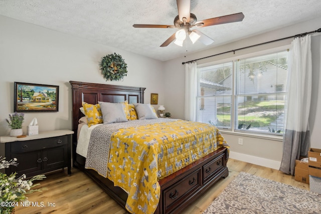 bedroom with ceiling fan, light hardwood / wood-style floors, and a textured ceiling