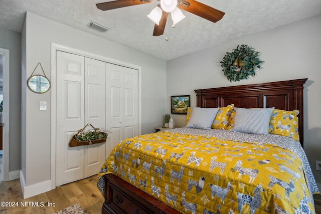 bedroom featuring a textured ceiling, light hardwood / wood-style flooring, ceiling fan, and a closet