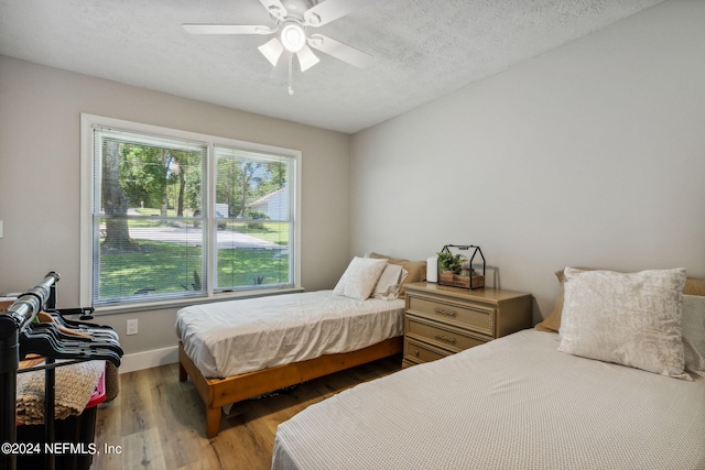 bedroom with a textured ceiling, ceiling fan, and hardwood / wood-style flooring