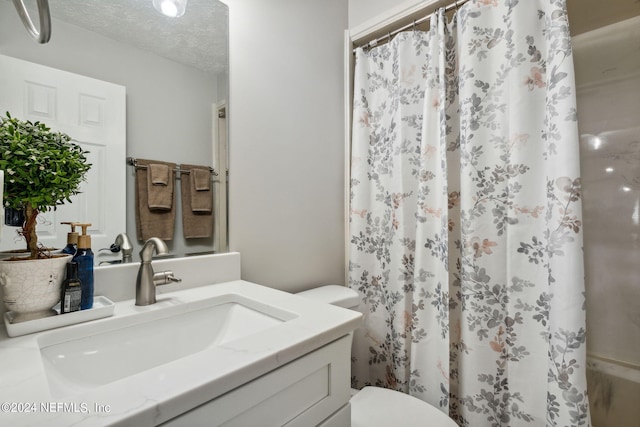 bathroom featuring vanity, a textured ceiling, toilet, and walk in shower