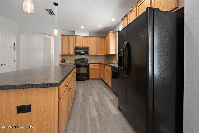 kitchen with a kitchen island, black appliances, pendant lighting, backsplash, and light hardwood / wood-style floors