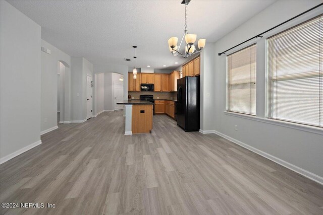 kitchen with a center island, light hardwood / wood-style floors, a notable chandelier, black appliances, and pendant lighting