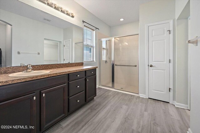 bathroom with vanity, a textured ceiling, hardwood / wood-style floors, and a shower with shower door