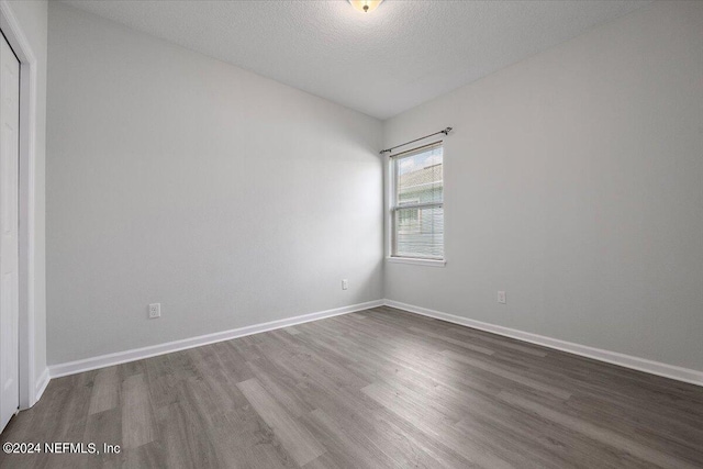 empty room with dark wood-type flooring and a textured ceiling