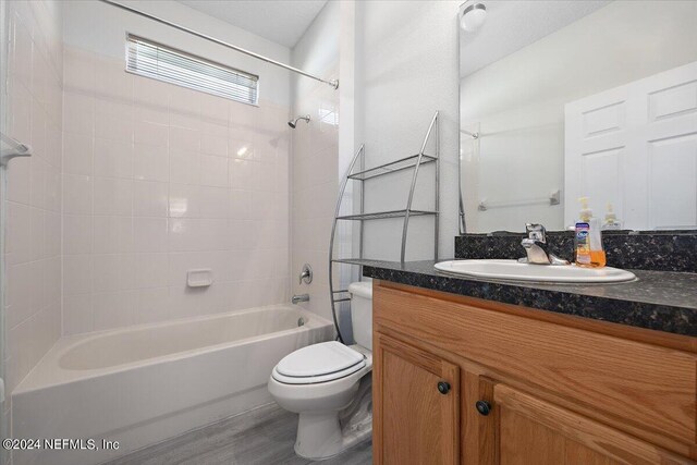 full bathroom featuring vanity, toilet, tiled shower / bath combo, and wood-type flooring