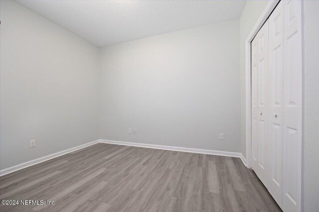 unfurnished bedroom with a textured ceiling, wood-type flooring, and a closet