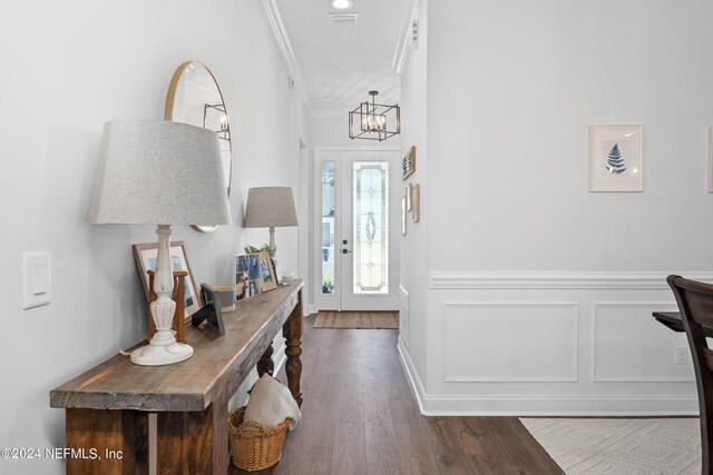 entryway with ornamental molding, dark hardwood / wood-style floors, and a notable chandelier