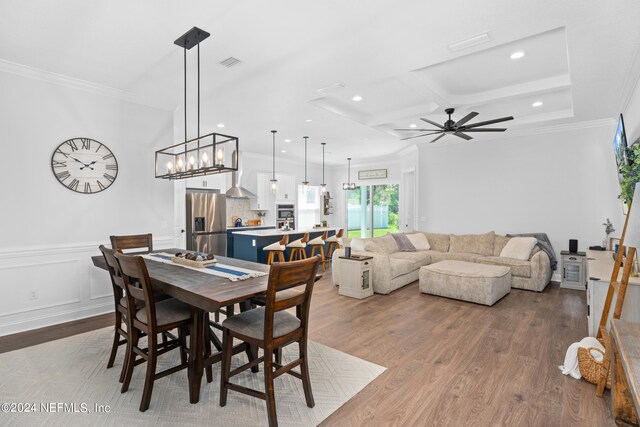 dining area featuring ceiling fan with notable chandelier, coffered ceiling, and light hardwood / wood-style flooring