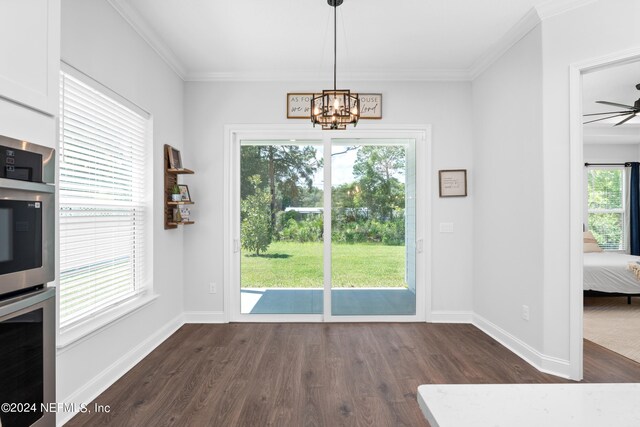 interior space with ceiling fan with notable chandelier, plenty of natural light, dark hardwood / wood-style flooring, and ornamental molding