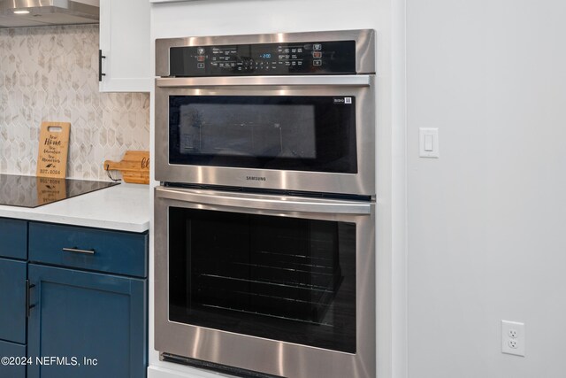 kitchen featuring black electric stovetop, double oven, extractor fan, and blue cabinetry