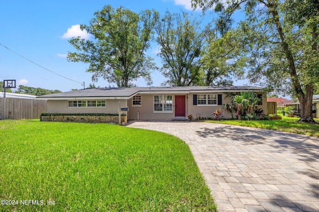 ranch-style home featuring fence, a front lawn, and decorative driveway