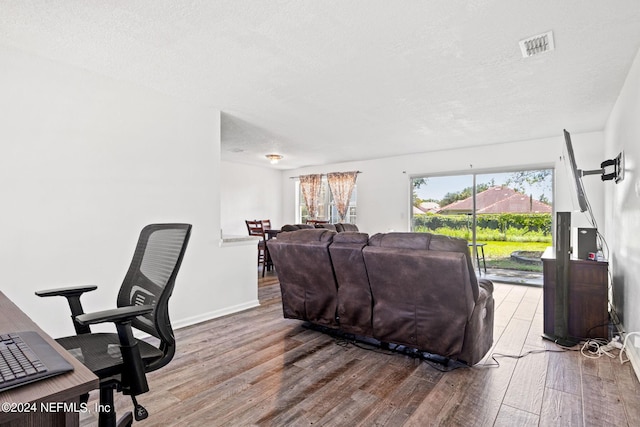 office area featuring visible vents, a textured ceiling, baseboards, and wood finished floors