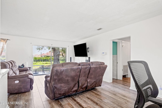 living area featuring visible vents, a textured ceiling, and wood finished floors