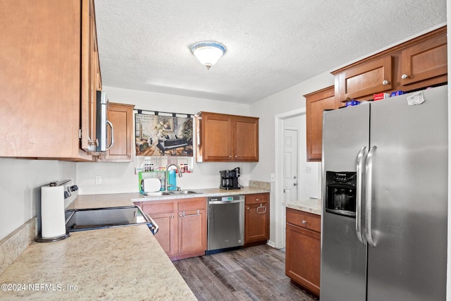 kitchen featuring appliances with stainless steel finishes, light countertops, a sink, and dark wood-style floors